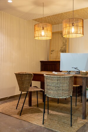 A dining area with wicker chairs, a wooden table, and a modern flat-screen monitor. - Hostal Es Niu de Tamariu (Palafrugell)