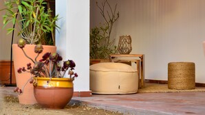 A cozy outdoor seating area with a terracotta pot, a wooden bench, and a hanging light fixture. - Hostal Es Niu de Tamariu (Palafrugell)