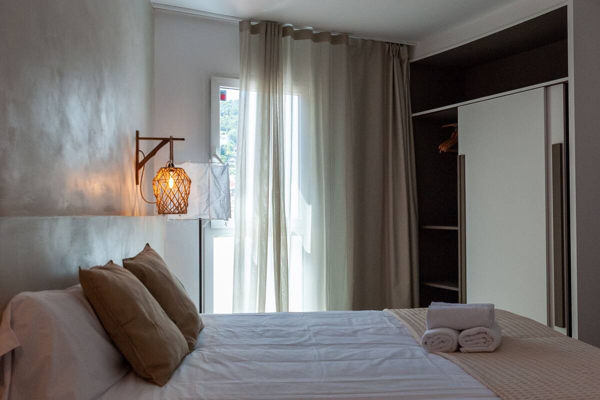 Un dormitorio moderno con una cama grande, una mesita de noche, una lámpara colgante y un armario con espejo.