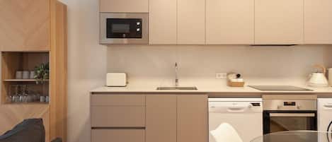Uma cozinha moderna com micro-ondas, forno, lava-louças e uma mesa de vidro.