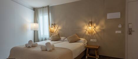 A hotel room with a large bed, two bedside lamps, a small wooden stool, and a round rug.