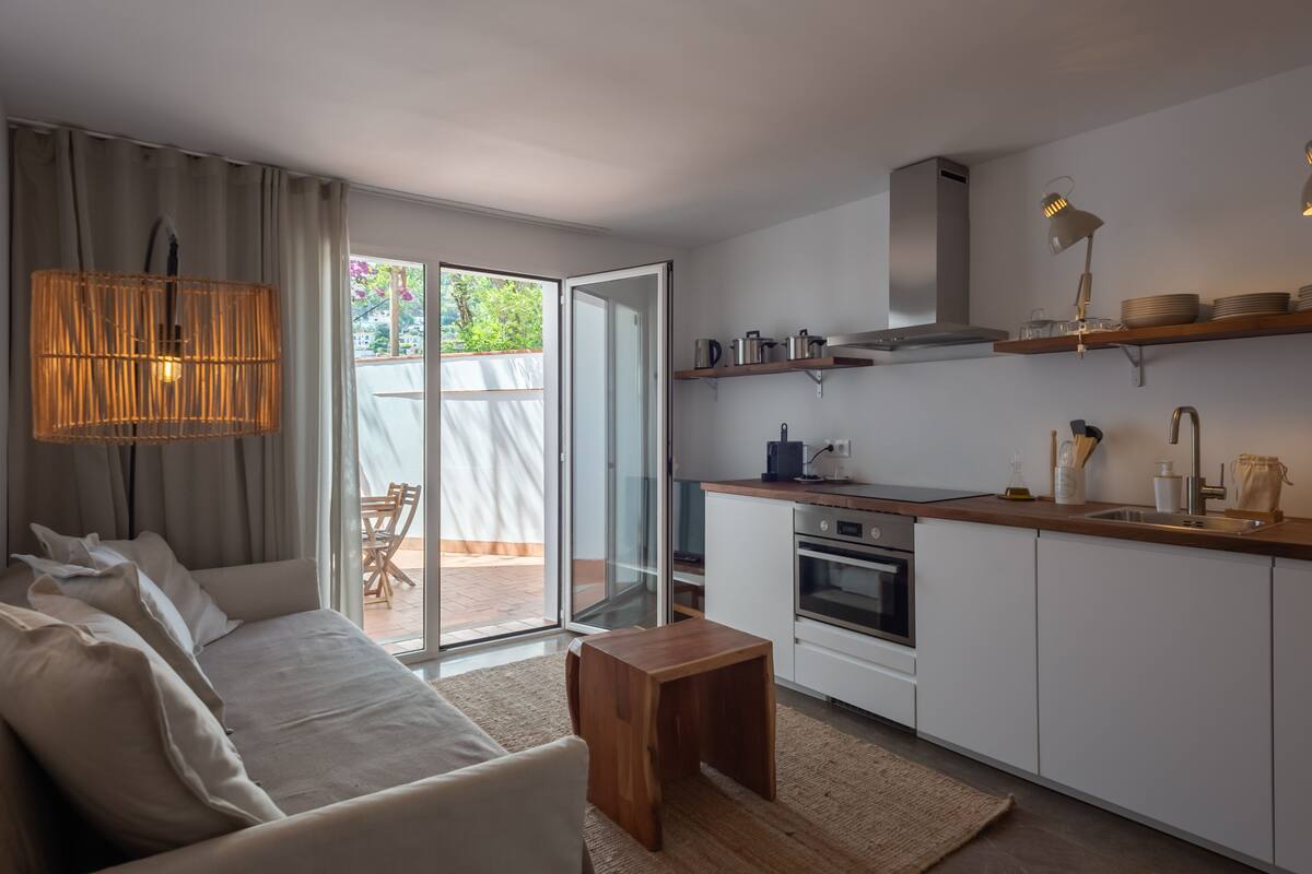 Una cocina moderna con encimera de madera, horno empotrado y lámpara colgante.