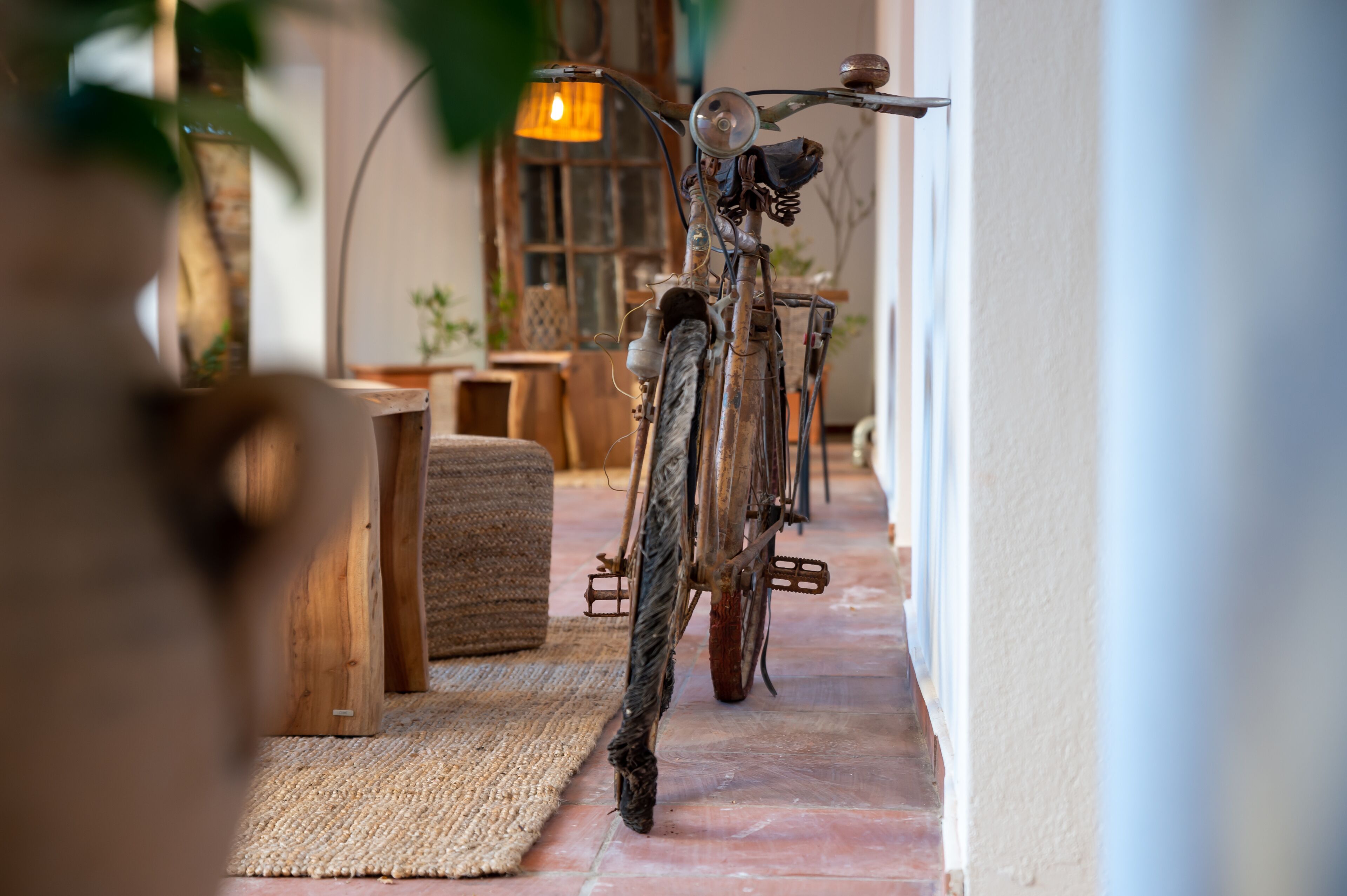 A rustic interior with a wooden bench, a woven rug, and a vintage bicycle leaning against a wall.