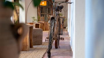 A rustic interior with a wooden bench, a woven rug, and a vintage bicycle leaning against a wall.