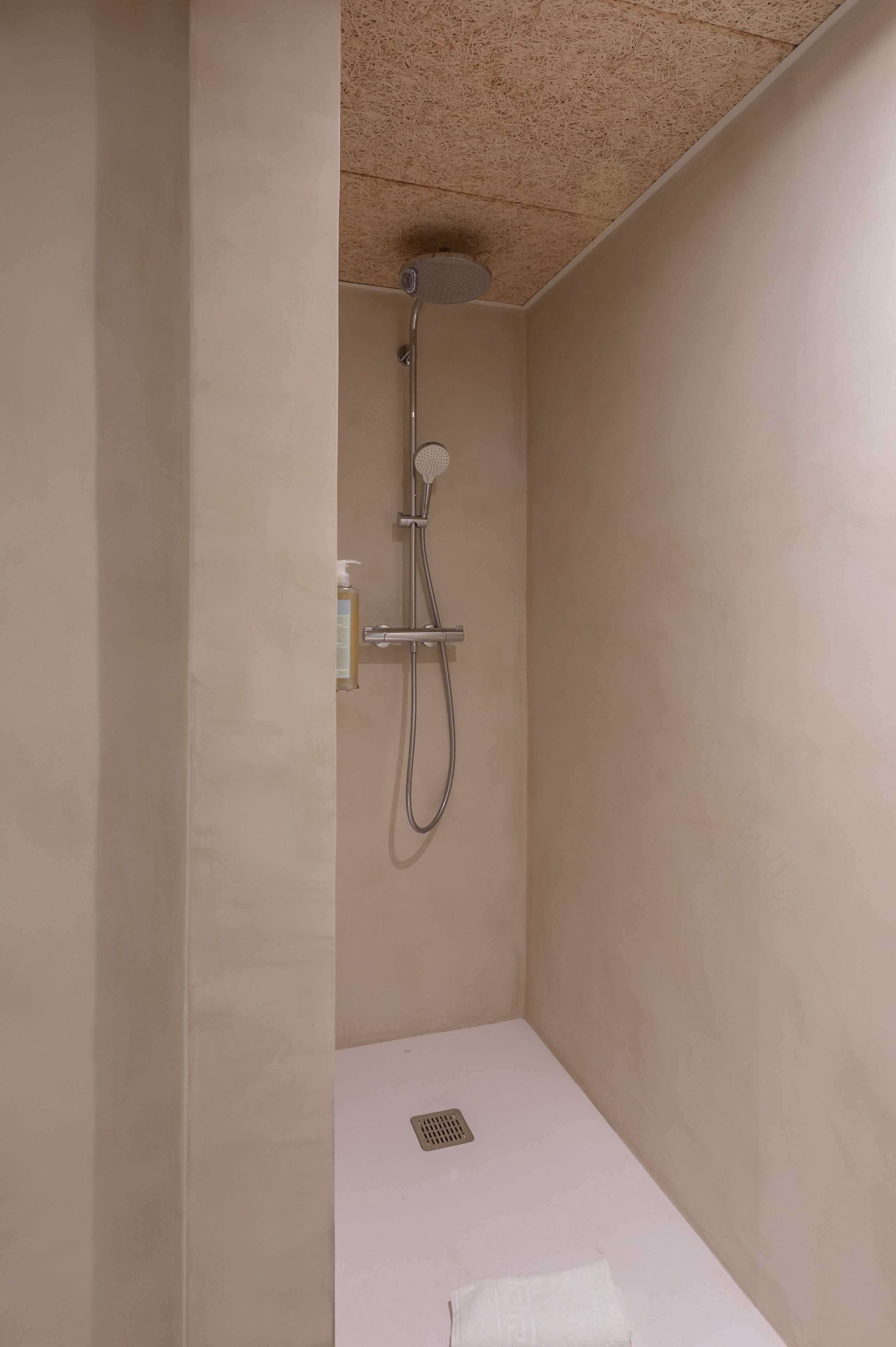 Un área de ducha pequeña y cerrada, con ducha de mano y un dispensador de champú.