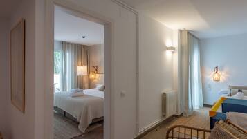 A hotel room with a bed, a chair, a radiator, and a nightstand with a lamp.