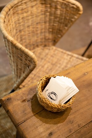 Una silla de mimbre con una cesta llena de cartas sobre una mesa de madera.
