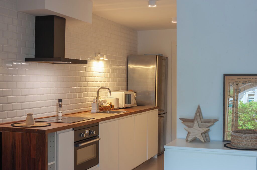 A modern kitchen with white subway tiles, stainless steel appliances, and a wooden countertop.