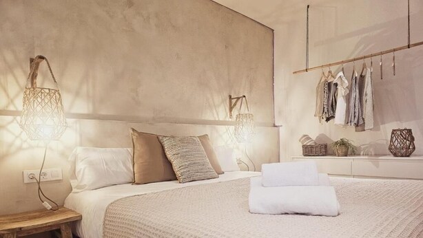 A bedroom with a large bed, bedside lamps, a nightstand, and a wall-mounted wardrobe. - Hostal Es Niu de Tamariu (Palafrugell)