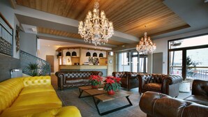 A spacious living area with leather sofas, a coffee table, and a chandelier. - Wifi, 50m from resort center, fitness, swimming pool, sauna, hammam, balcony, tv, ski locker, 45m² (Les Arcs)