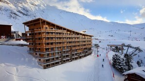 A multi-story hotel with balconies, situated in a snowy mountainous area with ski slopes in the background. - Wifi, 50m from resort center, fitness, swimming pool, sauna, hammam, balcony, tv, ski locker, 45m² (Les Arcs)