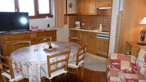 Een gezellige keuken met houten kastjes, een betegelde spatwand en een eethoek met een ronde tafel en stoelen.