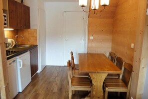 Una cocina compacta con una mesa y sillas de madera, un lavamanos y una cafetera.