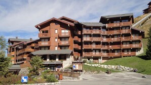 Een meerhoog hotel met houten balkons en een gevel van natuursteen.