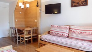 Een gezellige kamer met een houten bank, een klein tafeltje en een eethoek met stoelen.