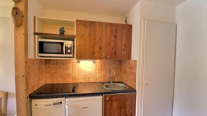 Een kleine keuken met een magnetron, spoelbak en vaatwasser.