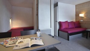 A compact hotel room with a bed, a small table with magazines, and a bench. - Ski-in/ski-out & foot of the slopes, 2nd floor, balcony, tv, 28m², La Plagne (La Plagne)
