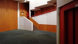 A hallway with a carpeted floor, wooden walls, a staircase with red railings, and a red door. - 50m from ski slopes, 3rd floor, view forest, tv, 33m², Les Arcs (Les Arcs)