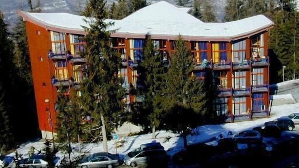 A multi-story hotel with a curved roof, surrounded by snow-covered mountains and pine trees. - 50m from ski slopes, 3rd floor, view forest, tv, 33m², Les Arcs (Les Arcs)