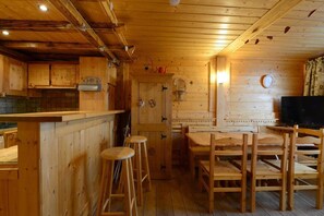 A wooden interior with a bar area, stools, a dining table, and a television. - 10m from resort center, 9th floor, view mountain, balcony, tv, 35m², La Plagne (Aime)