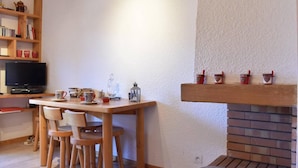 A cozy living room with a wooden table, chairs, a television, and a fireplace. - 200m from ski slopes, 4th floor, balcony, tv, ski locker, 35m², Méribel (Méribel - Les Allues)