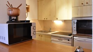 A compact kitchen with a microwave, oven, and sink. - 200m from ski slopes, 4th floor, balcony, tv, ski locker, 35m², Méribel (Méribel - Les Allues)