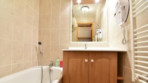 A bathroom with a bathtub, a wooden cabinet, a mirror, and a towel rack. - 150m from ski slopes, 2nd floor, balcony, tv, ski locker, 45m², Valloire (Valloire)