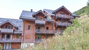 A multi-story wooden building with balconies, likely a hotel or lodge, set in a natural, hilly area. - 150m from ski slopes, 2nd floor, balcony, tv, ski locker, 45m², Valloire (Valloire)
