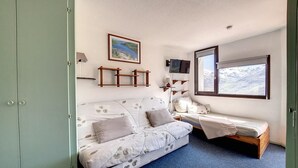 A small, cozy room with a sofa and a single bed, a TV, a window with a view, and a framed picture on the wall. - 2nd floor, tv, ski locker, 26m², Les Menuires (Les Menuires)