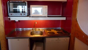 Une petite cuisine équipée comprenant un évier, une cuisinière, un four à micro-ondes et un petit réfrigérateur.