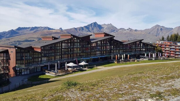 Un hôtel composé de plusieurs bâtiments, doté d’une terrasse et offrant une vue sur un paysage montagneux.