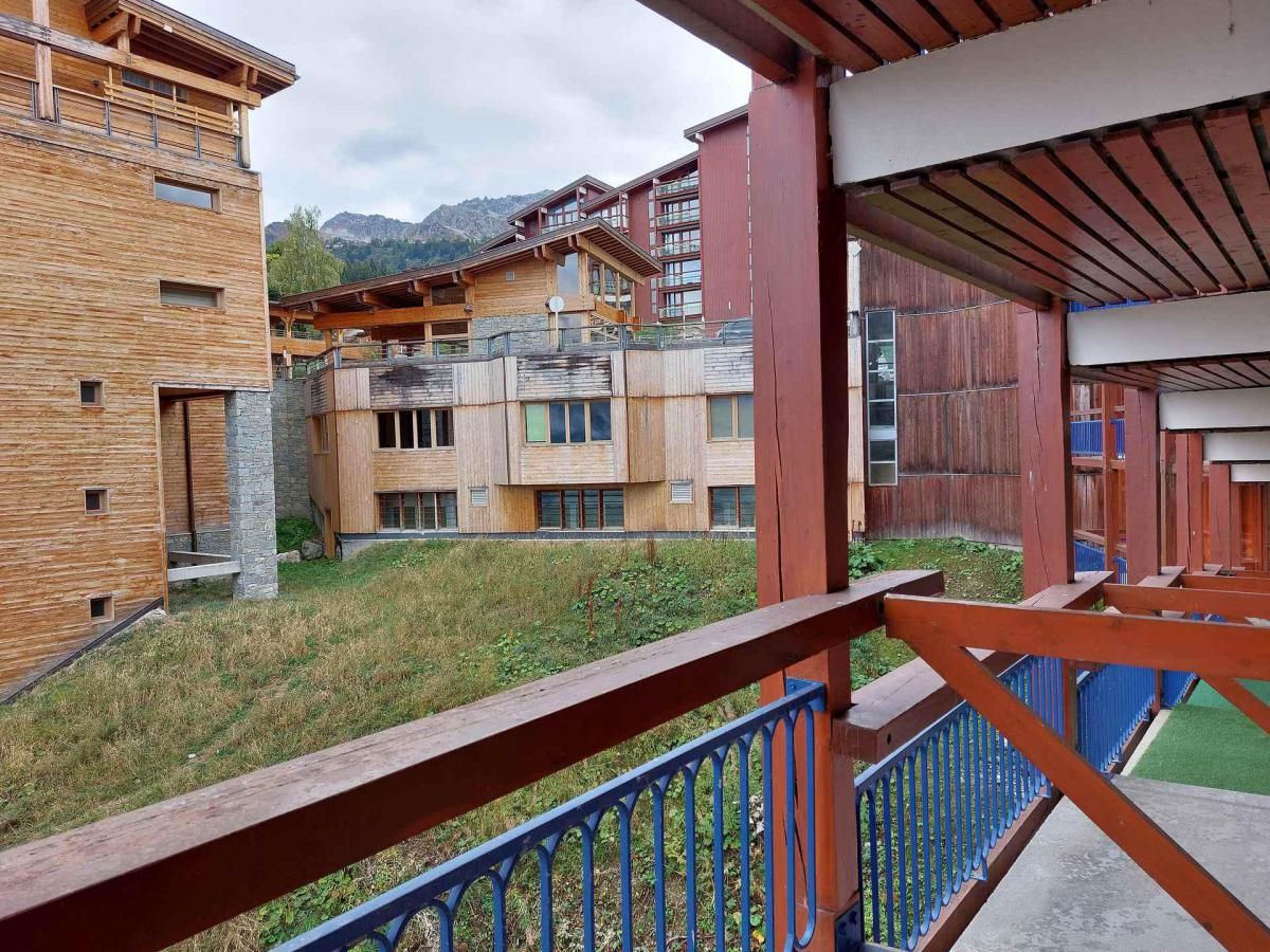 A modern building with a wooden facade, balconies, and a view of mountains.