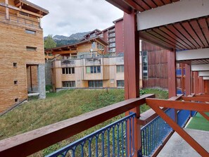 A modern building with a wooden facade, balconies, and a view of mountains.
