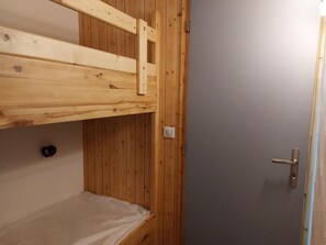Simple, compact room with a bunk bed and a single door.
