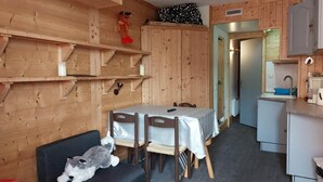 A cozy cabin-style room with a dining table, chairs, a sofa, and a kitchen area with a sink and cabinets. - 50m from resort center, 6th floor, view mountain, tv, 19m², Les Arcs (Les Arcs)