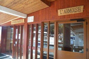 A wooden building with signs reading "LE GRAND D'ARBOIS" and "L'ARMOISE".