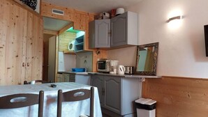 A compact kitchen with a dining area, wooden walls, a microwave, a kettle, and a trash bin. - 50m from resort center, 6th floor, view mountain, tv, 19m², Les Arcs (Les Arcs)