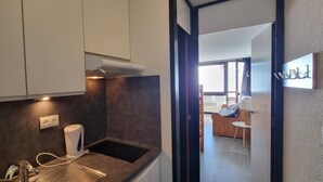 A modern kitchen with a built-in stove, a kettle, and a small sink.