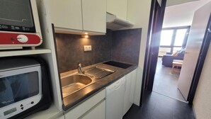 A compact kitchen with a stainless steel sink, a microwave, and a dishwasher.