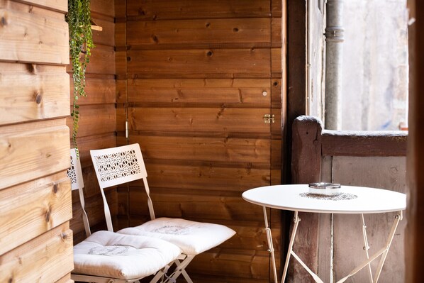 Une cabane en bois avec une chaise blanche et une petite table ronde.