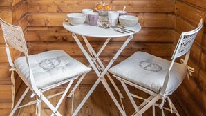 A wooden cabin with a dining table and two chairs, a hanging plant, and a small shelf with a plant. - Cosmo incroyable idéal famille rue Carnot (Annecy)