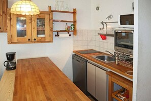 A kitchen with wooden cabinets, a built-in oven, a coffee maker, and a sink. - 15m from ski slopes, 2nd floor, view ski slopes, balcony, 40m², Les Orres (Les Orres)