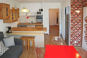 A compact kitchen with wooden cabinets, a built-in oven, and a microwave.