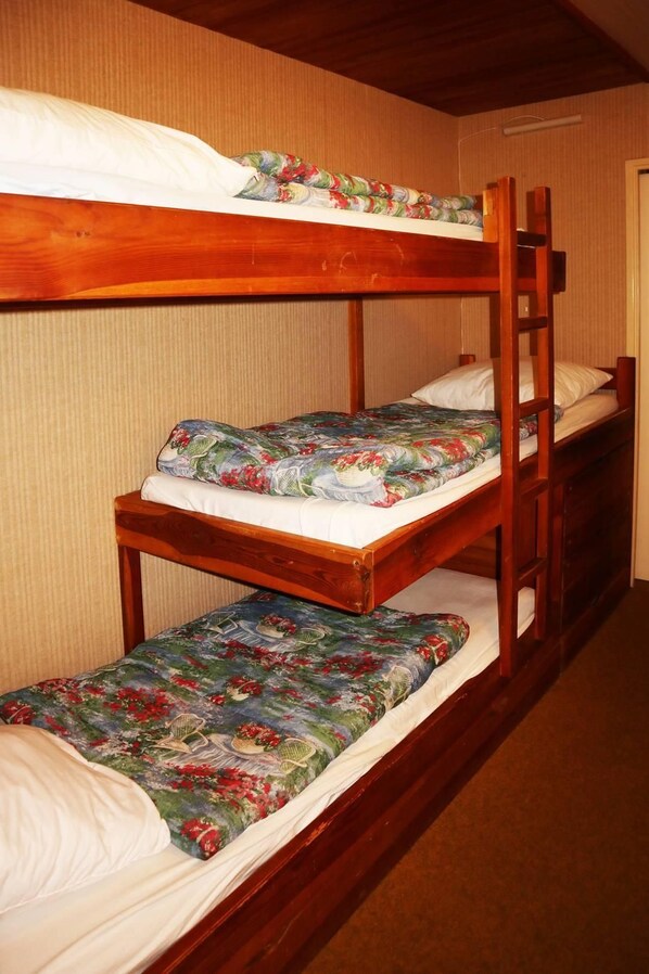Ein Stockbett mit floralem Bettbezug und Holzrahmen in einem Zimmer mit Streifenmuster an den Wänden.