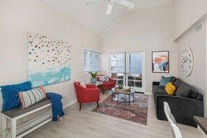 A spacious living room with a high ceiling, a large window, and a view of the outdoors.