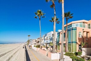 A beachfront hotel with a row of palm trees, a sandy beach, and a clear blue sky. - Beachside 3 BD in the Heart of Mission Beach! (San Diego)