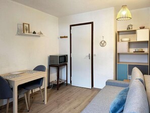 Cozy living space with a dining table, TV, sofa, and shelving unit.