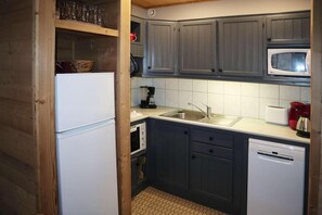 A compact kitchen with a refrigerator, microwave, sink, and coffee maker.