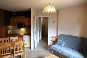 Un espacio habitable compacto con kitchenette, comedor y sofá.