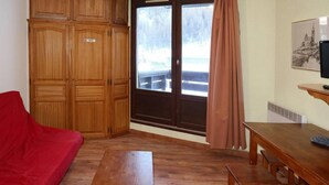 A room with a wooden wardrobe, a red sofa, a wooden table, and a bench. - Ski-in/ski-out & foot of the slopes, 4th floor, view ski slopes, balcony, tv, 22m², Les Orres (Les Orres)